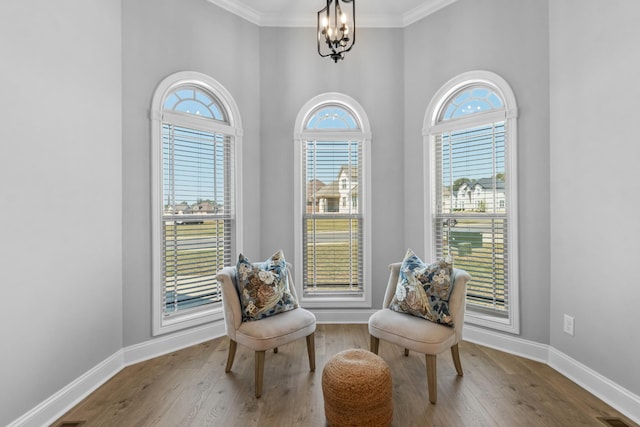 living area with visible vents, a notable chandelier, ornamental molding, wood finished floors, and baseboards