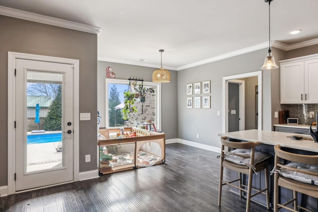 dining space featuring dark wood-style floors, baseboards, and ornamental molding