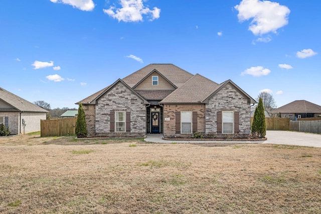 view of front of house with a shingled roof, a front lawn, and fence