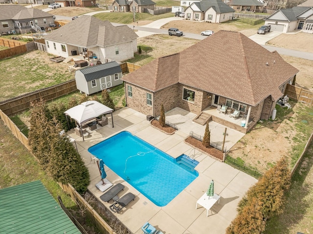 view of swimming pool featuring a fenced in pool, a residential view, a gazebo, a fenced backyard, and a patio area