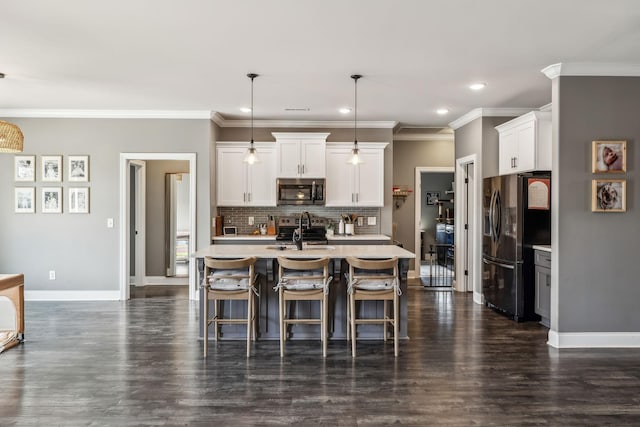 kitchen featuring baseboards, a sink, decorative backsplash, light countertops, and stainless steel appliances