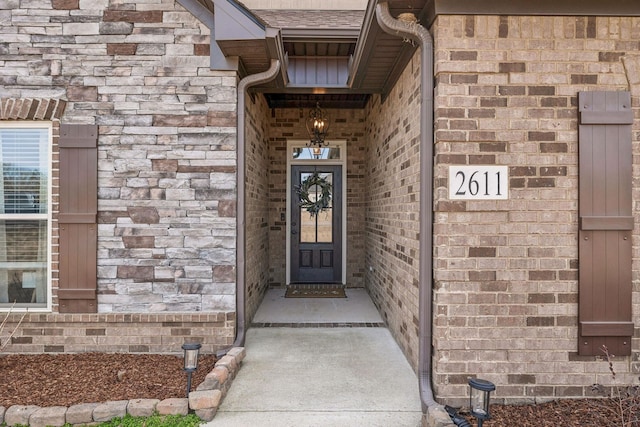 property entrance featuring stone siding, brick siding, and roof with shingles