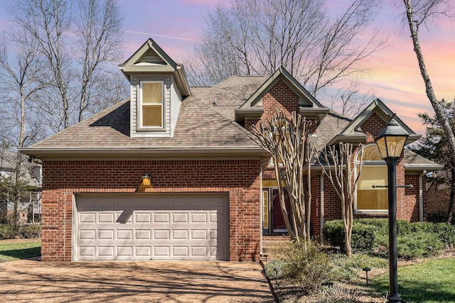 view of front of house with brick siding, an attached garage, a shingled roof, and driveway