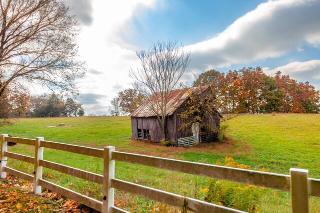 view of yard with a rural view, a barn, an outdoor structure, and fence