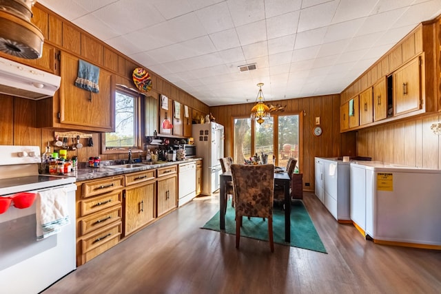 kitchen with visible vents, washer and clothes dryer, under cabinet range hood, white appliances, and a sink