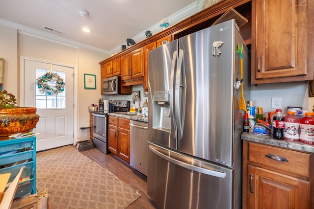 kitchen featuring visible vents, brown cabinets, stainless steel appliances, and ornamental molding