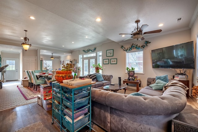 living area with recessed lighting, wood finished floors, visible vents, and ornamental molding