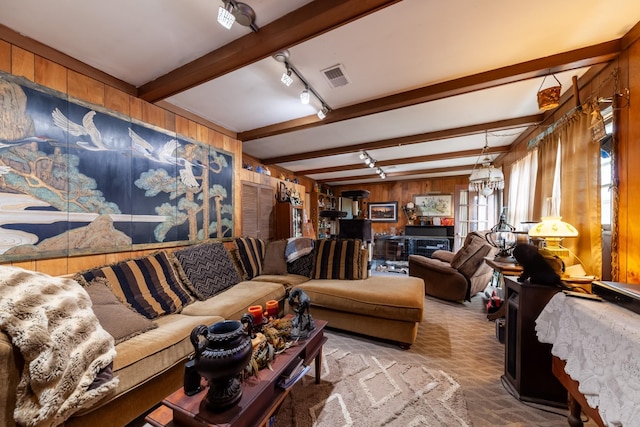 living room featuring track lighting, beamed ceiling, visible vents, and wood walls