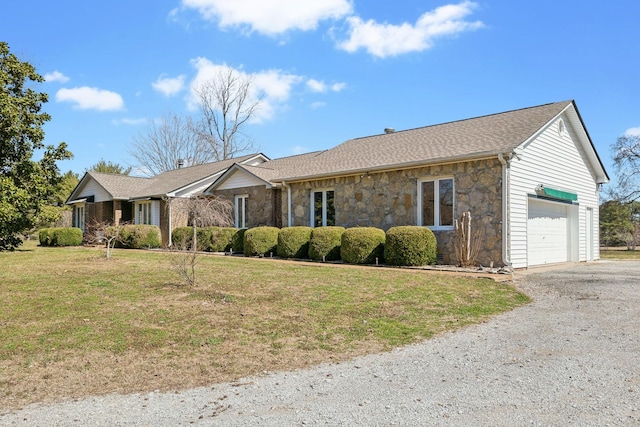 single story home with aphalt driveway, stone siding, a front yard, and a garage