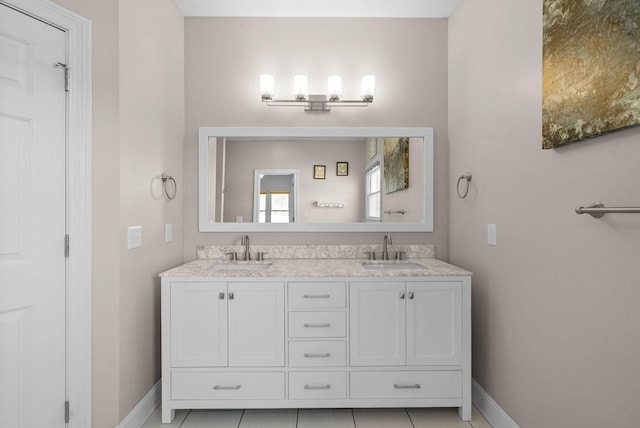 full bathroom with double vanity, baseboards, and a sink