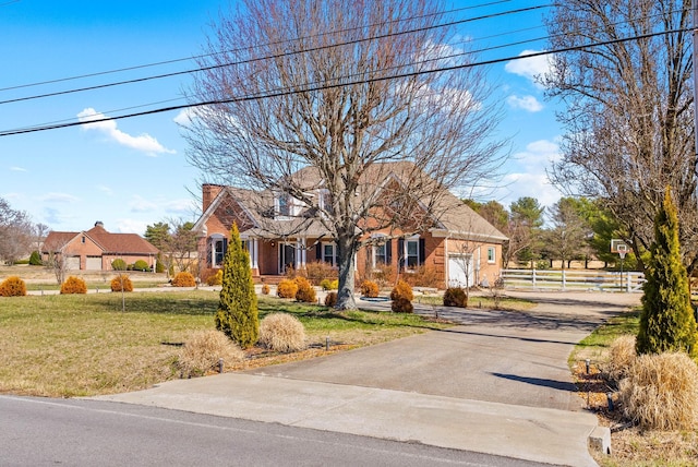 cape cod-style house featuring a front lawn, fence, driveway, and a chimney