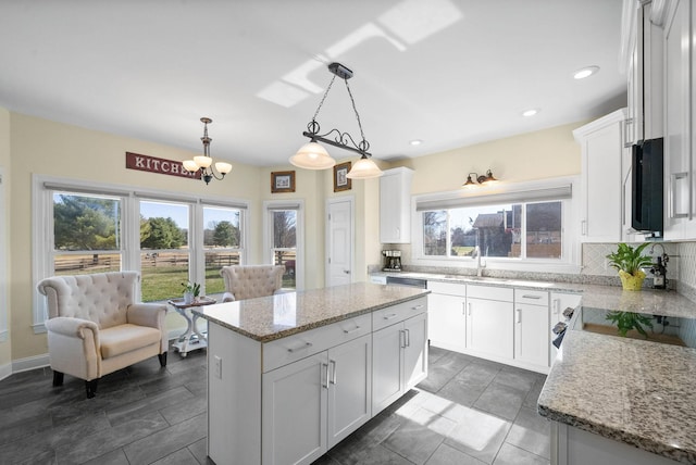 kitchen with stainless steel microwave, backsplash, a center island, and white cabinetry