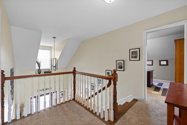 hall featuring vaulted ceiling, an upstairs landing, carpet, and baseboards