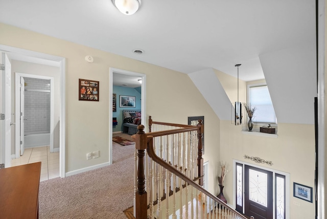 corridor featuring visible vents, baseboards, lofted ceiling, carpet floors, and an upstairs landing