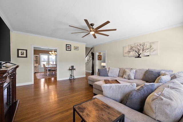 living area with ceiling fan with notable chandelier, stairway, crown molding, baseboards, and dark wood-style flooring