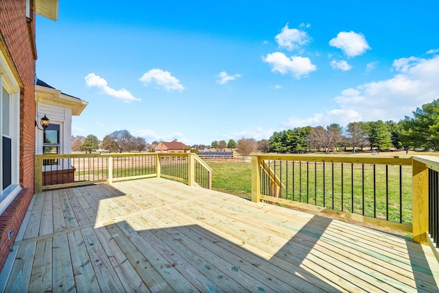 wooden terrace with a rural view and a yard