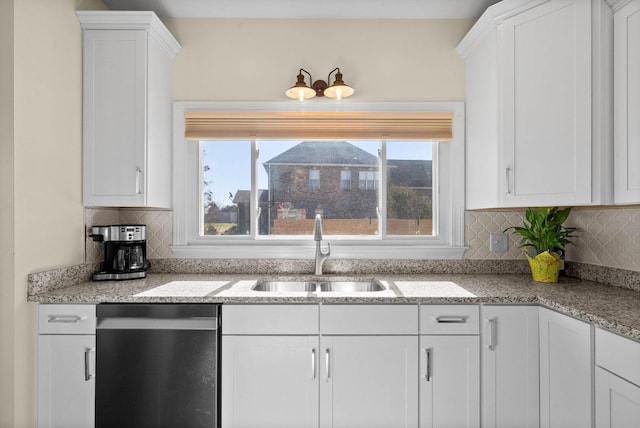 kitchen with stainless steel dishwasher, backsplash, white cabinetry, and a sink