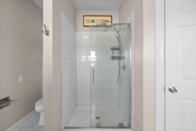 bathroom featuring tile patterned floors, toilet, baseboards, and a stall shower