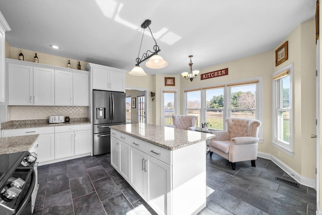 kitchen with a center island, decorative backsplash, white cabinets, stove, and stainless steel fridge