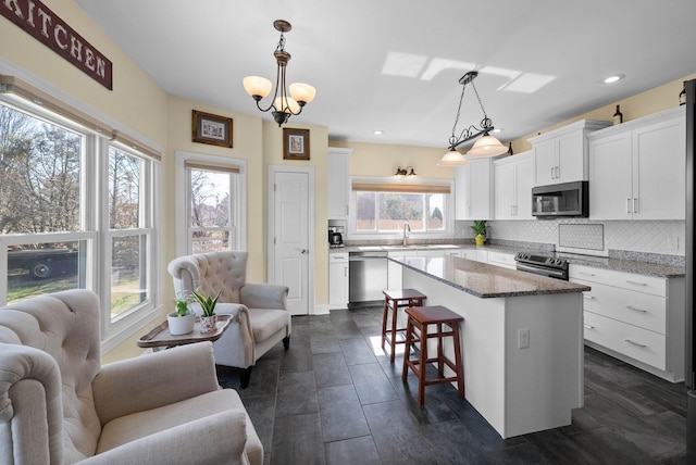 kitchen with a center island, open floor plan, decorative backsplash, stainless steel appliances, and white cabinetry