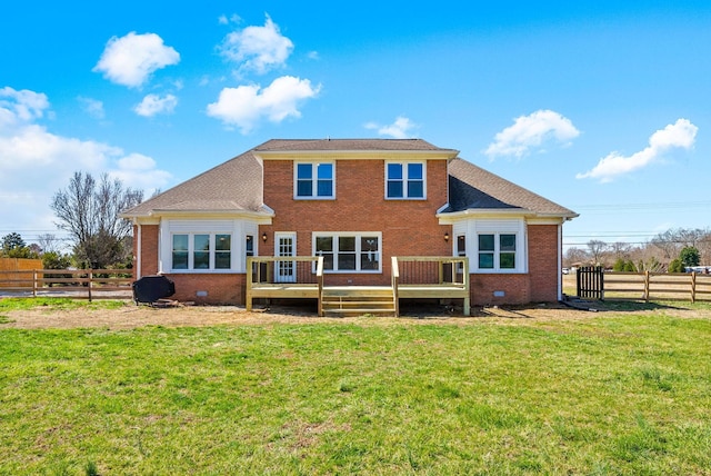 rear view of house with brick siding, fence, a lawn, a deck, and crawl space