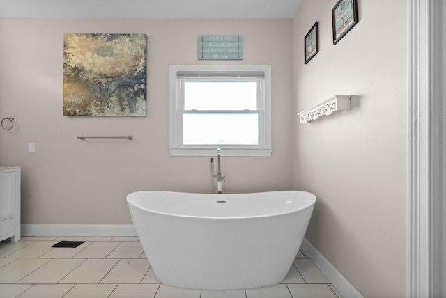 bathroom featuring a freestanding tub, baseboards, and tile patterned flooring