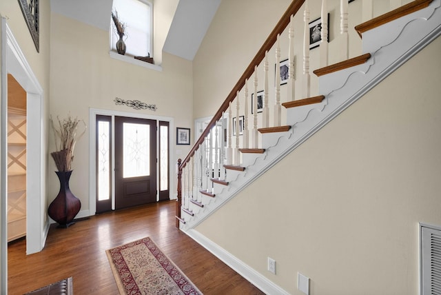 entrance foyer featuring stairway, baseboards, wood finished floors, and a towering ceiling