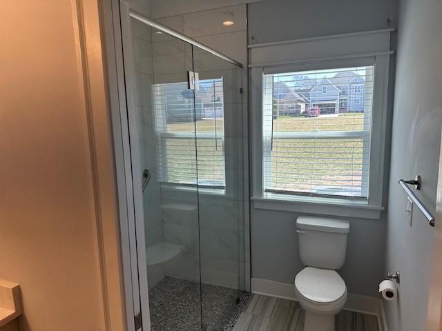 bathroom with baseboards, toilet, and a shower stall