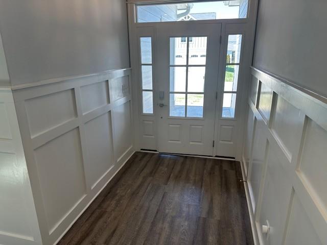 entryway featuring a wealth of natural light, dark wood-style floors, wainscoting, and a decorative wall