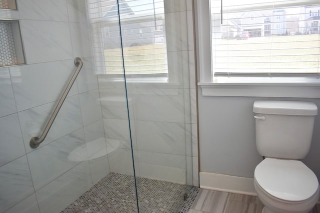 bathroom with a shower stall, toilet, and baseboards