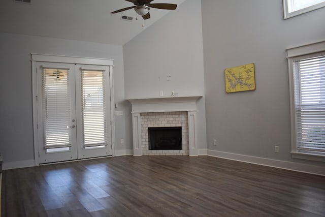 unfurnished living room featuring visible vents, a fireplace, french doors, wood finished floors, and high vaulted ceiling