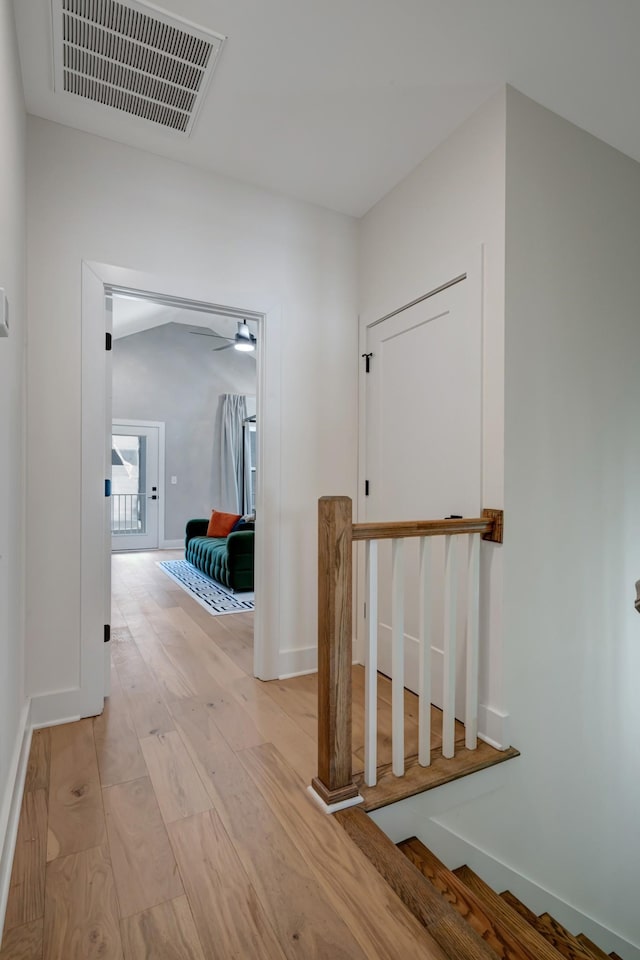 corridor with light wood-style floors, visible vents, and baseboards