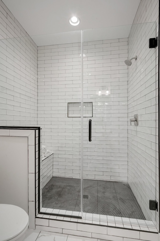 bathroom featuring toilet and a shower stall