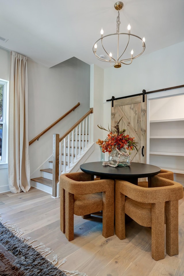 dining area with visible vents, stairs, a barn door, wood finished floors, and a notable chandelier