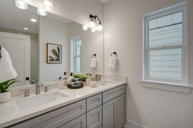 bathroom featuring a sink, baseboards, recessed lighting, and double vanity