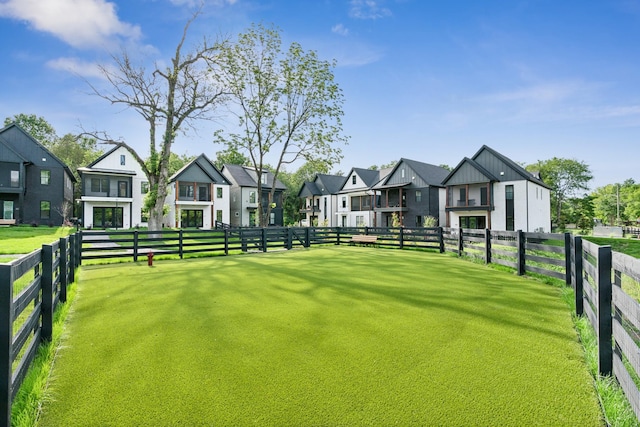 view of community with a yard, fence, and a residential view