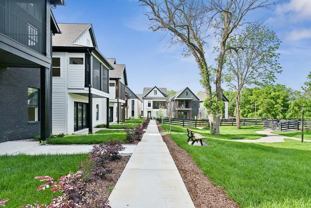 view of property's community with fence, a lawn, and a residential view