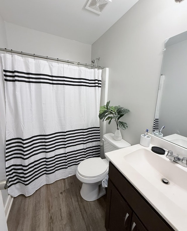 bathroom with vanity, toilet, wood finished floors, and visible vents