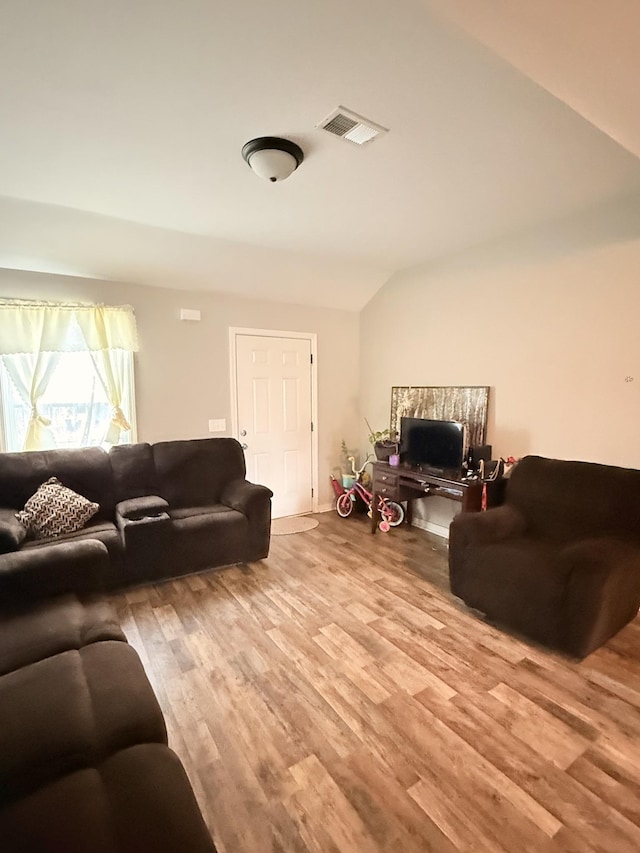 living area with lofted ceiling, wood finished floors, and visible vents