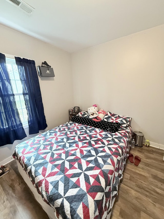 bedroom featuring visible vents, baseboards, and wood finished floors