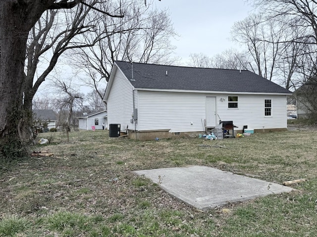 back of property with entry steps, central air condition unit, a lawn, and roof with shingles