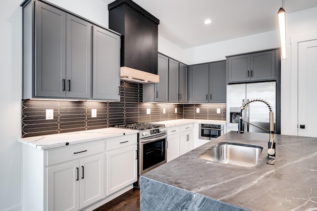 kitchen featuring dark wood-style floors, premium range hood, a sink, decorative backsplash, and stainless steel appliances