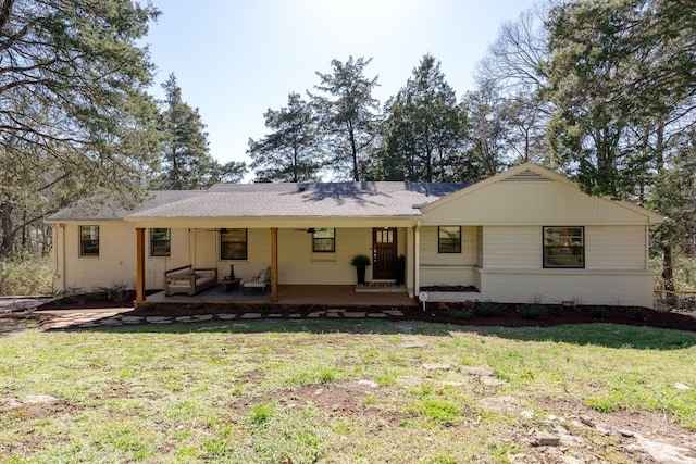 back of property with a ceiling fan, a lawn, and brick siding