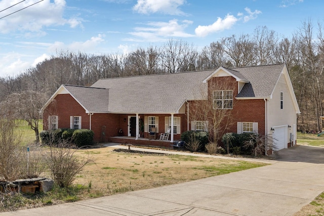 view of front of property with brick siding, a front yard, covered porch, driveway, and an attached garage