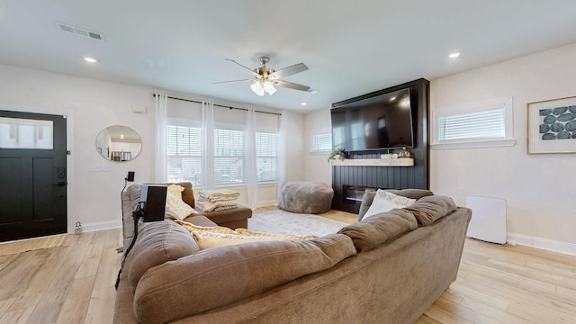 living room featuring visible vents, light wood-type flooring, and baseboards