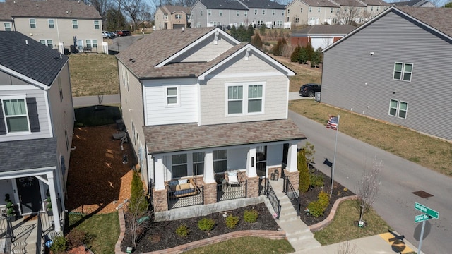 back of property with covered porch, a residential view, and roof with shingles