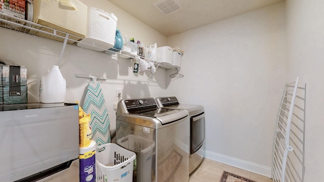 washroom featuring visible vents, baseboards, laundry area, light tile patterned flooring, and separate washer and dryer