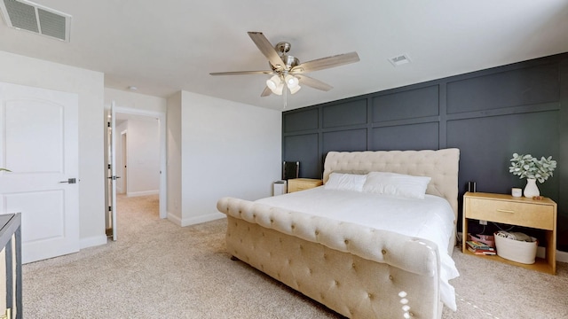 bedroom with ceiling fan, a decorative wall, visible vents, and light carpet