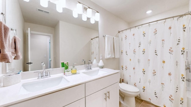 bathroom with double vanity, toilet, visible vents, and a sink