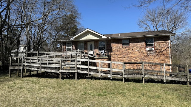 view of front facade featuring brick siding, a deck, and a front lawn